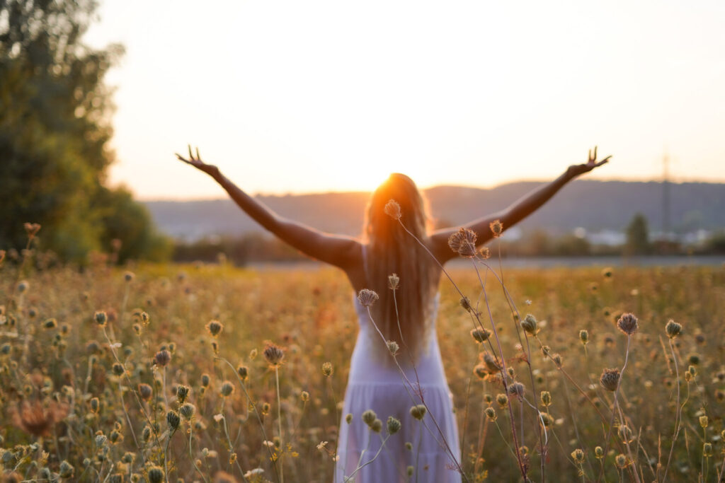 Veronica Albrecht steht in einem Feld und streckt der Sonne ihre Arme entgegen